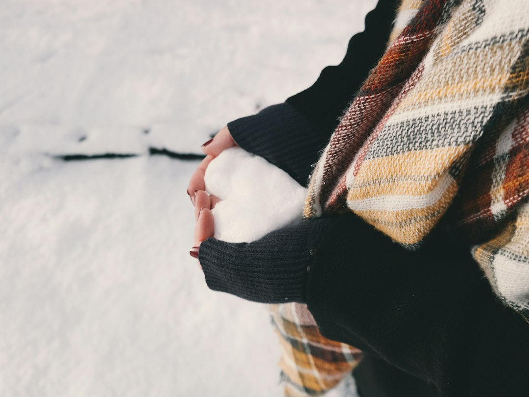 Hands holding snow outdoors in cold winter weather