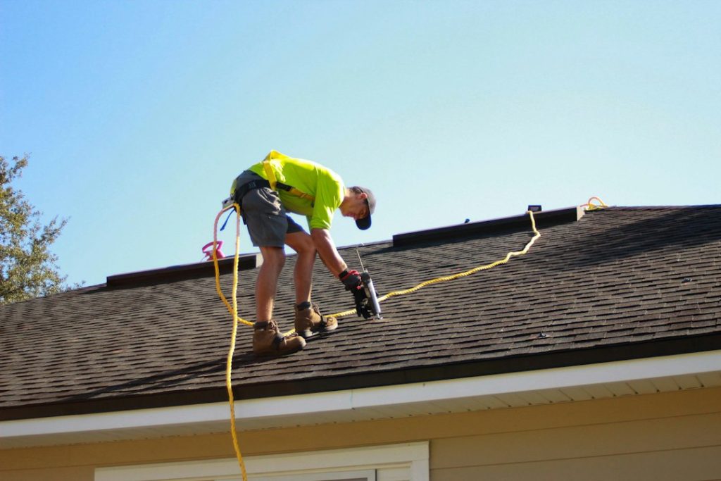 Worker inspecting or repairing a shingle roof