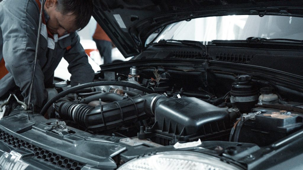Mechanic inspecting a car engine in an auto repair shop
